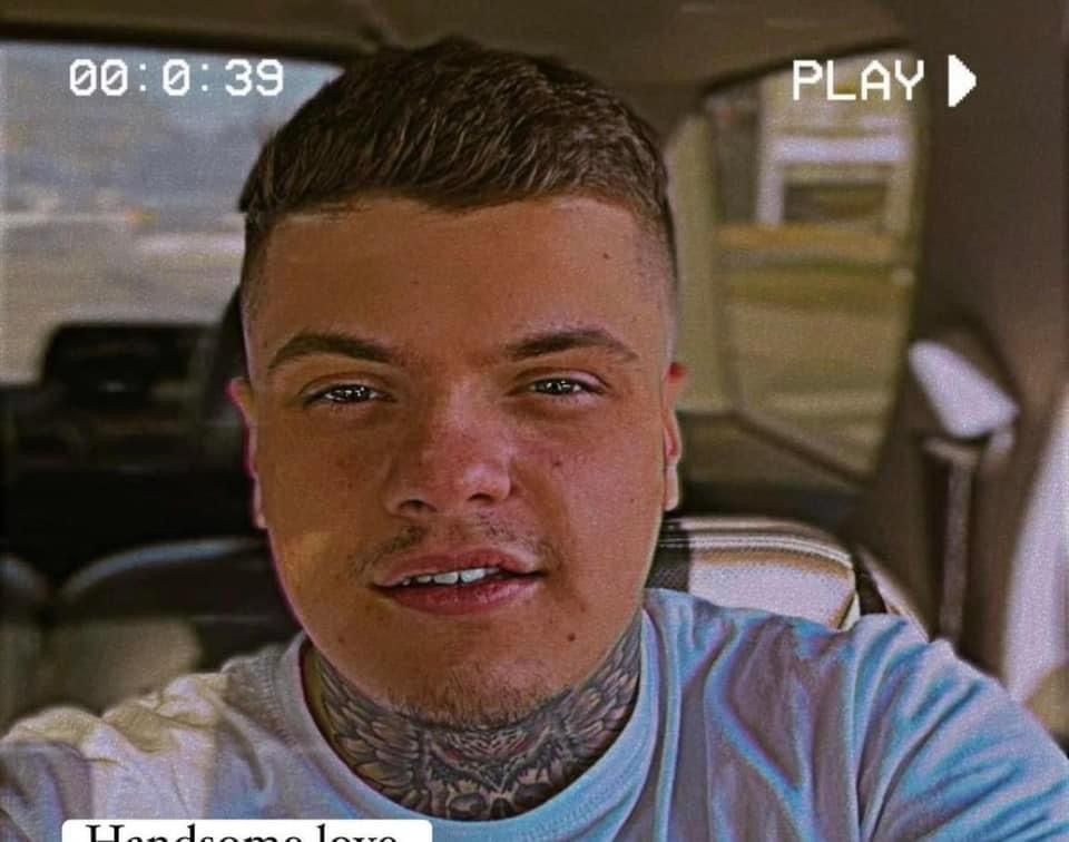 A man with a tattoo on his neck is taking a selfie in a car.