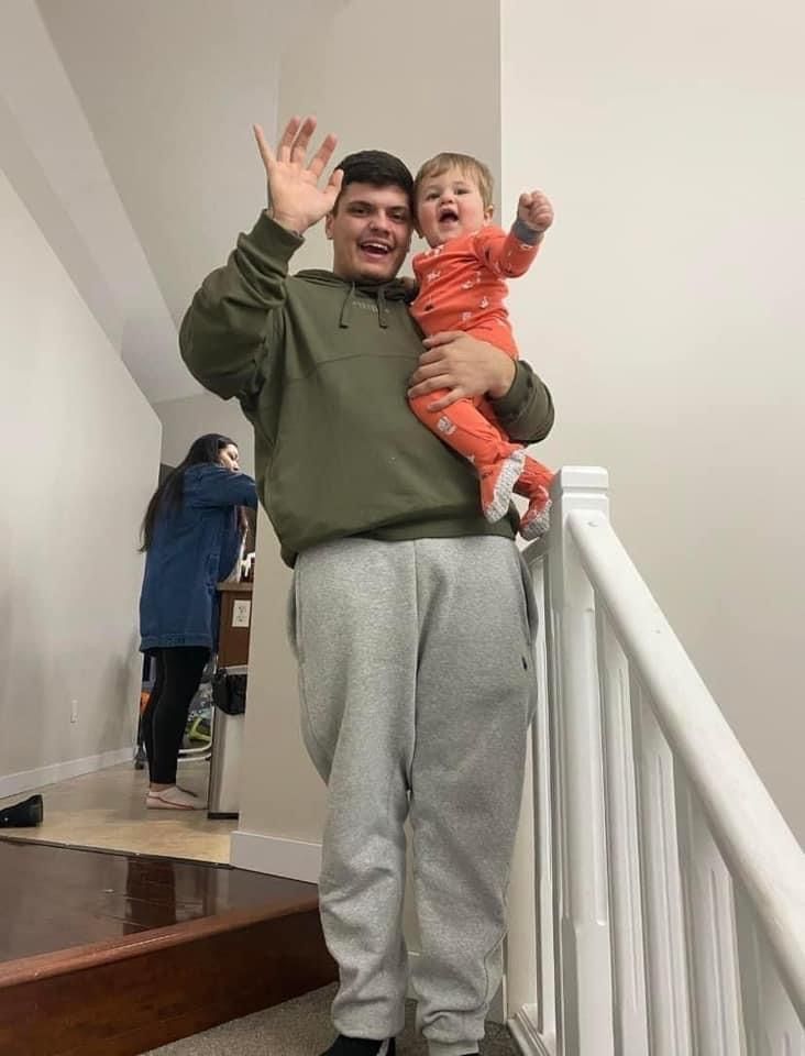 A man is holding a baby on top of a staircase.
