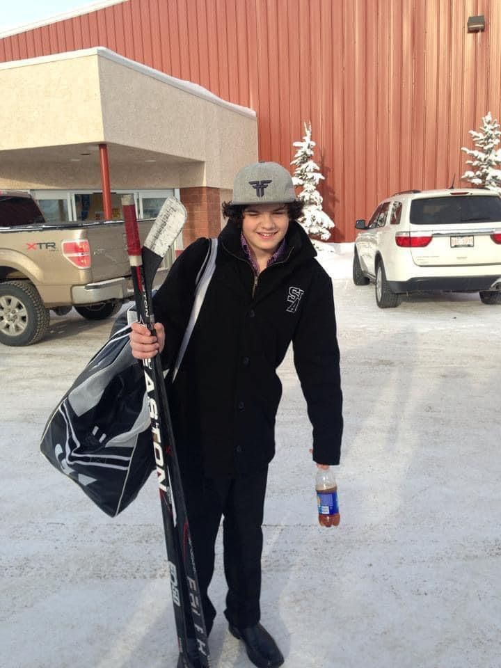 A person holding a hockey stick in front of a building