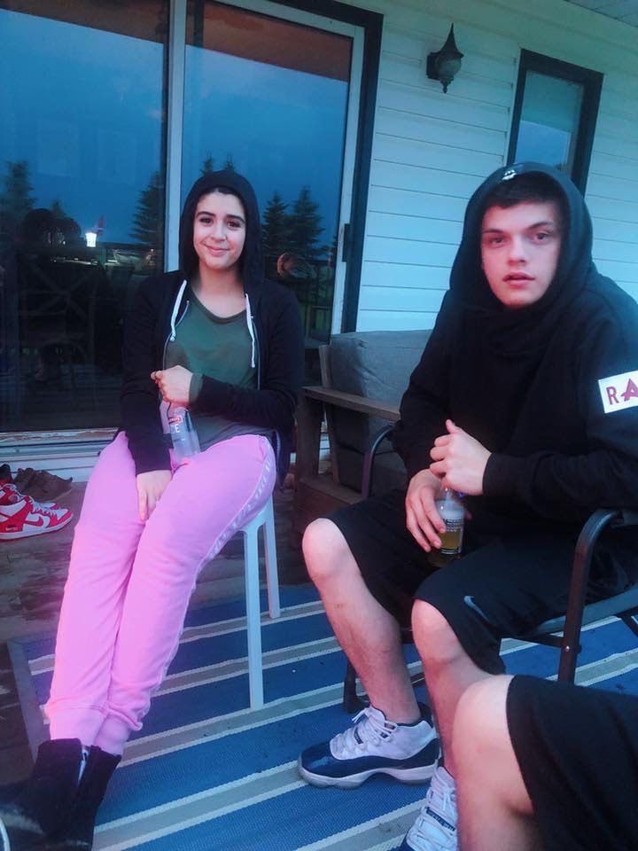 A girl in pink pants sits next to a boy in a black hoodie