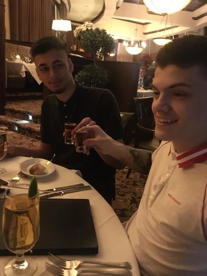 Two men are sitting at a table in a restaurant one is holding a shot glass