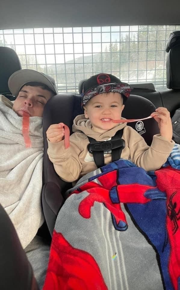 A man and a child are sitting in the back seat of a car.