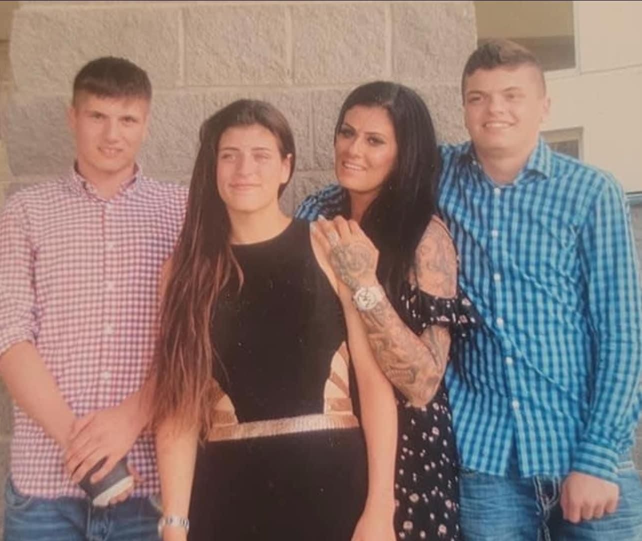 A group of people standing next to each other in front of a brick wall.