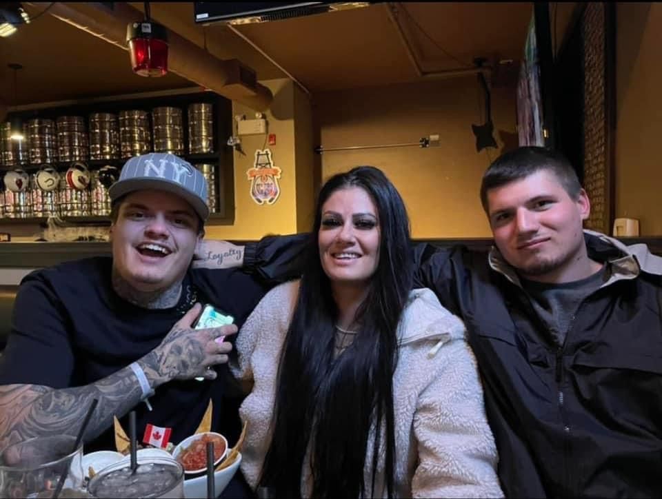 A man wearing a ny hat sits with two other people