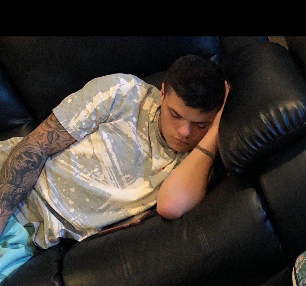 A man laying on a couch with his hand on his face