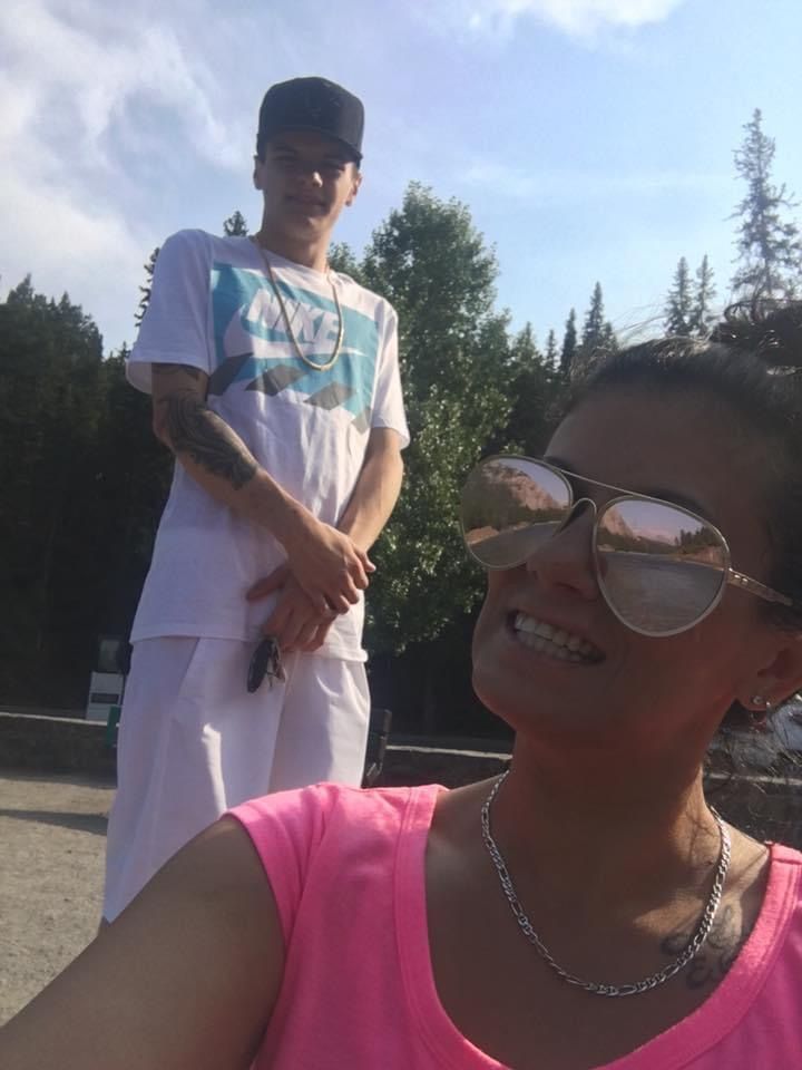 A woman wearing sunglasses stands next to a man with a tattoo on his arm