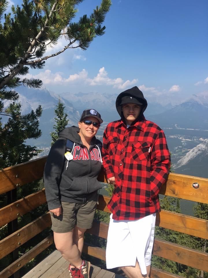 A man and a woman are standing next to each other on a balcony overlooking a mountain range.