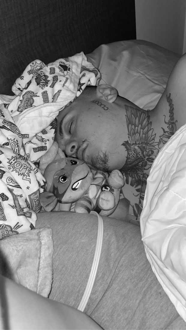 A black and white photo of a person sleeping with a stuffed animal.