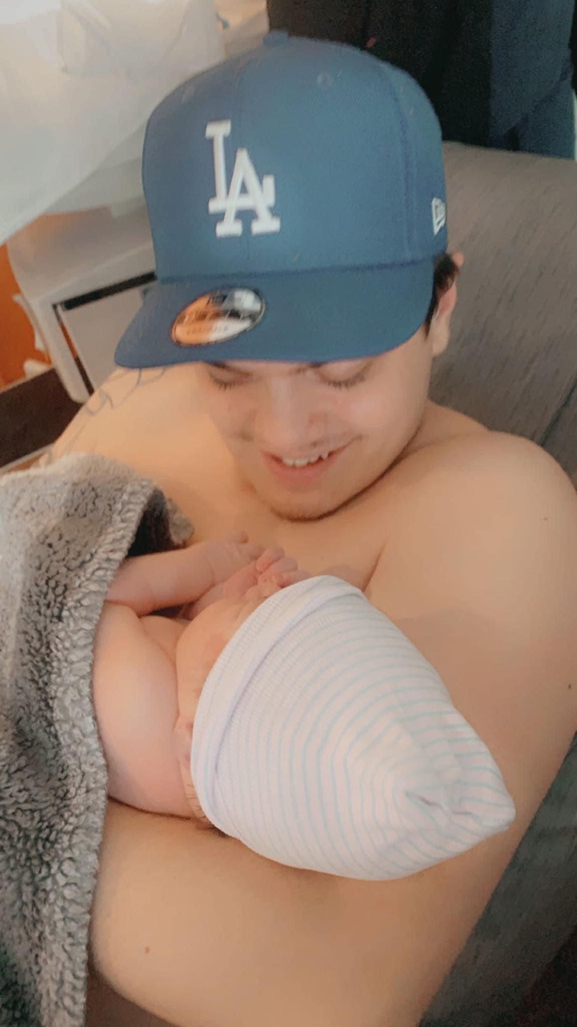 A man wearing a la hat is holding a baby in his arms.