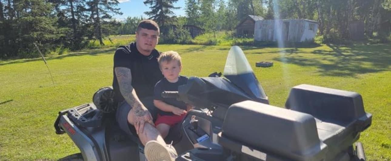 A man and a child are sitting on a snowmobile.