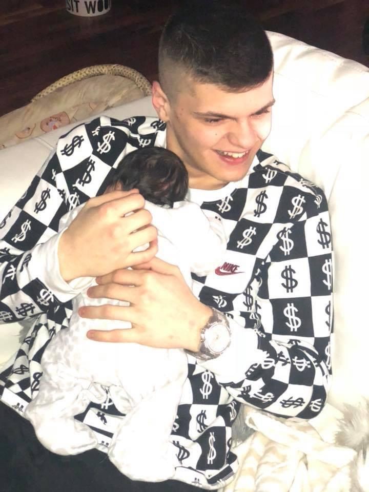 A man in a checkered shirt is holding a baby
