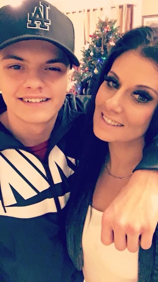 A man and a woman are posing for a picture in front of a christmas tree.