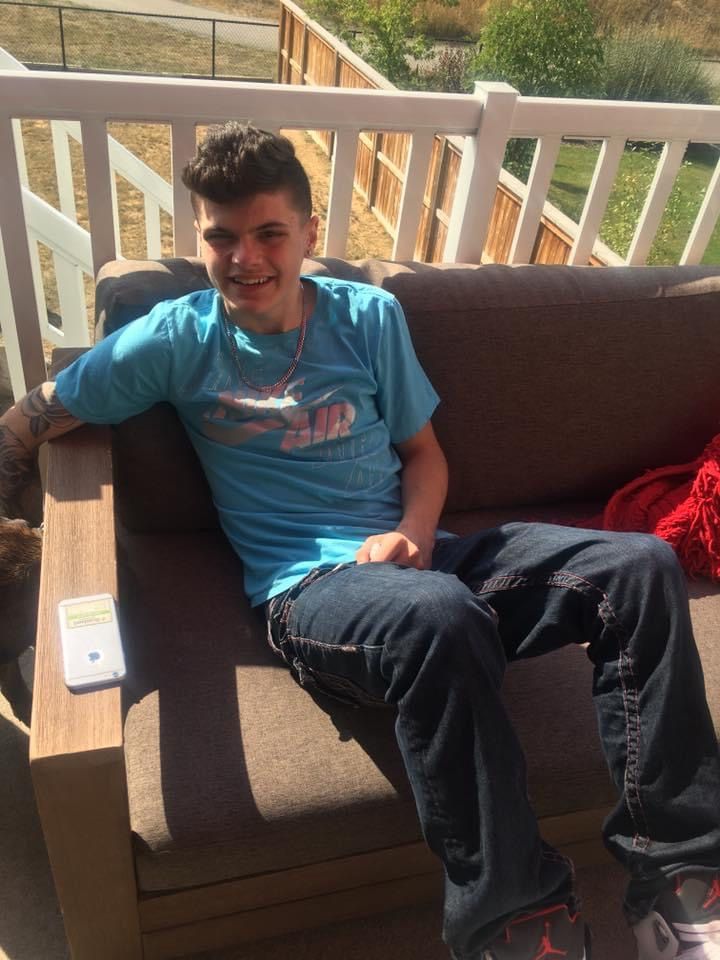 A boy in a blue shirt is sitting on a couch