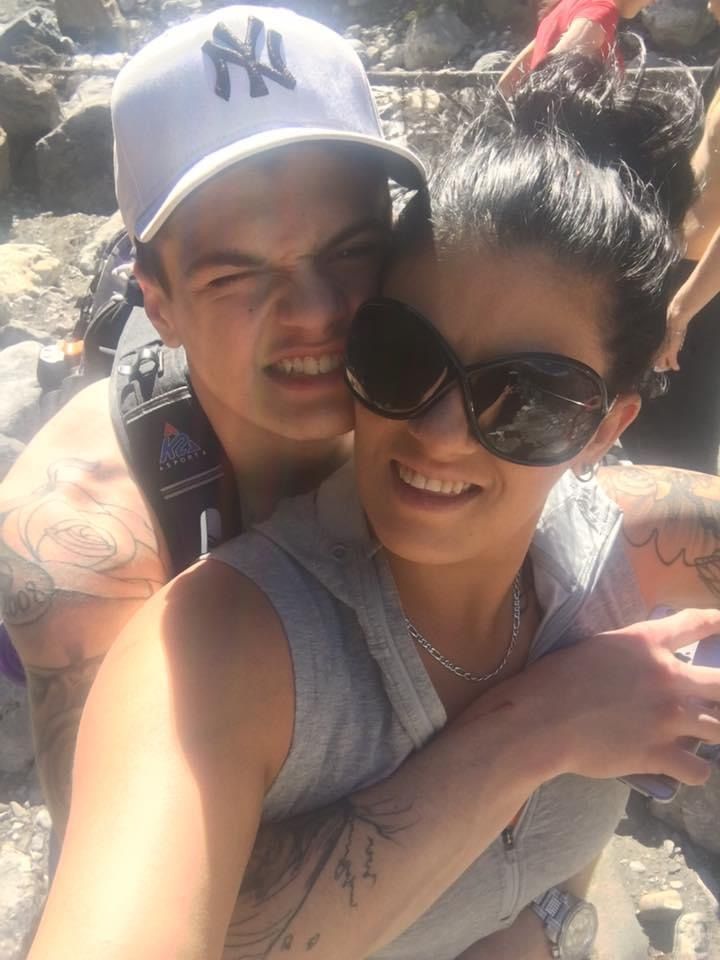 A man wearing a ny hat is hugging a woman wearing sunglasses.