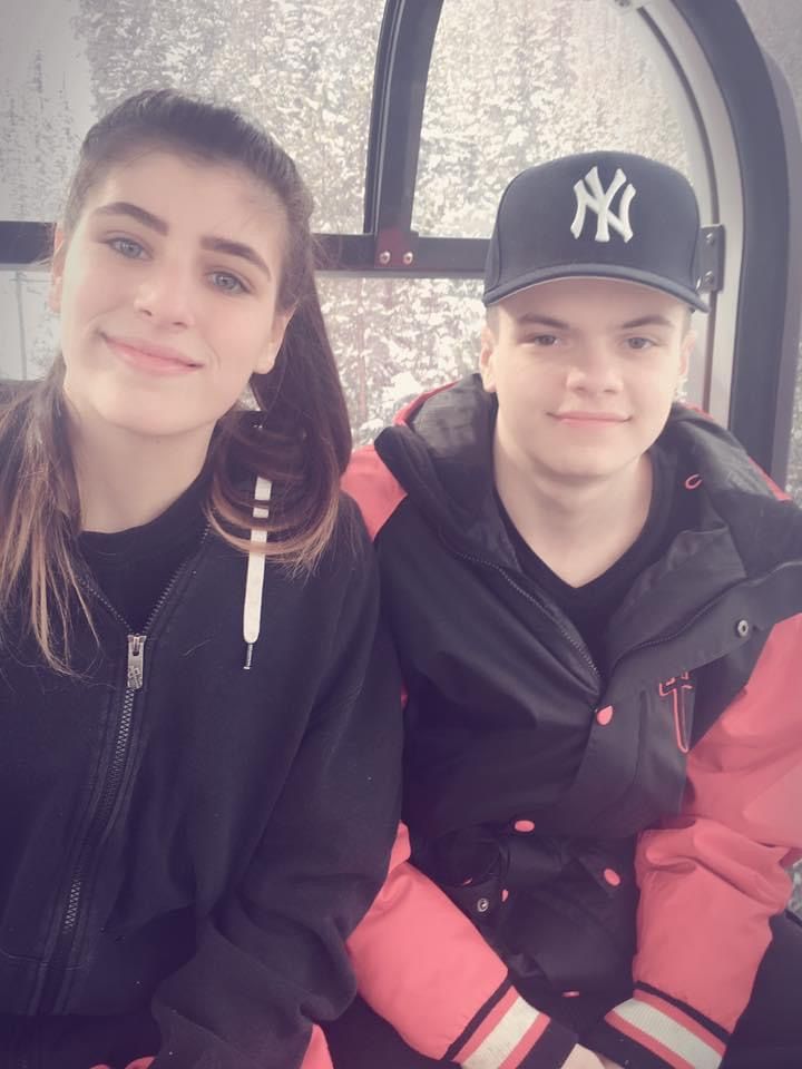 A boy wearing a ny hat sits next to a girl