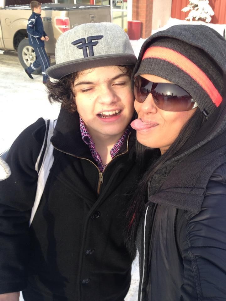 A woman sticking her tongue out next to a boy wearing a hat with the letter f on it