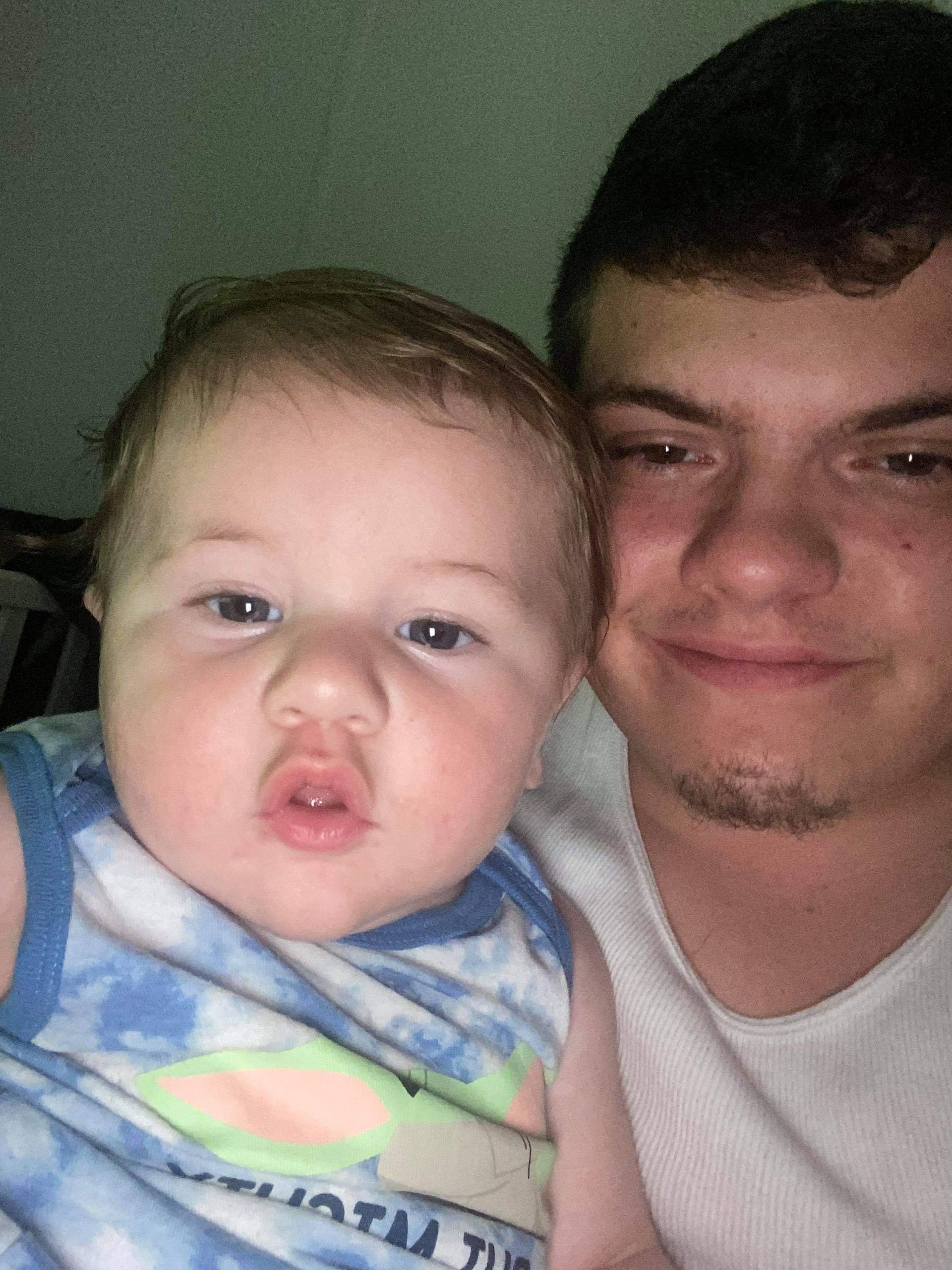 A man is holding a baby in his arms and smiling for the camera.