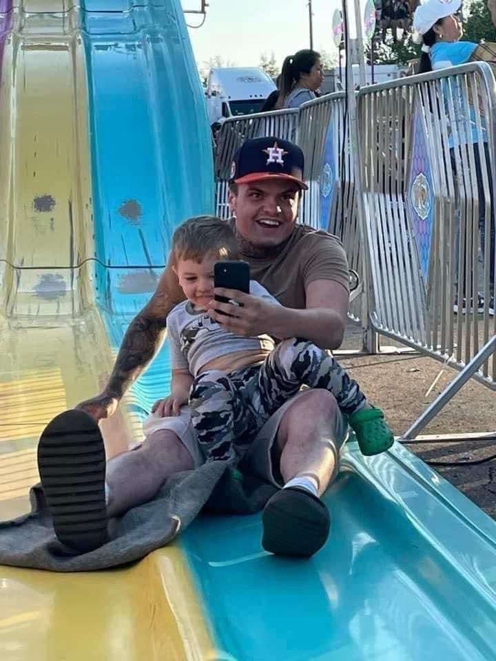 A man and a child are sitting on a slide at a carnival.