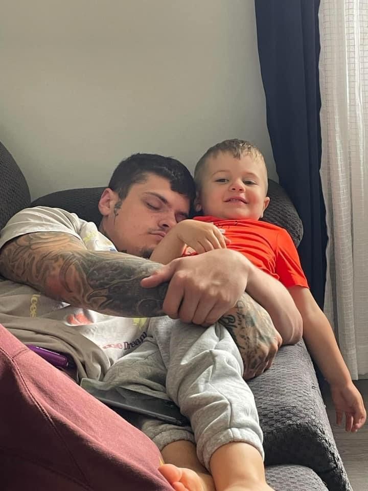 A man is sitting on a couch holding a little boy.