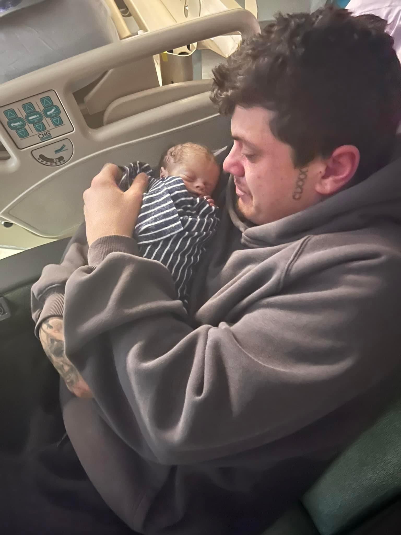 A man is holding a baby in his arms in a hospital bed.