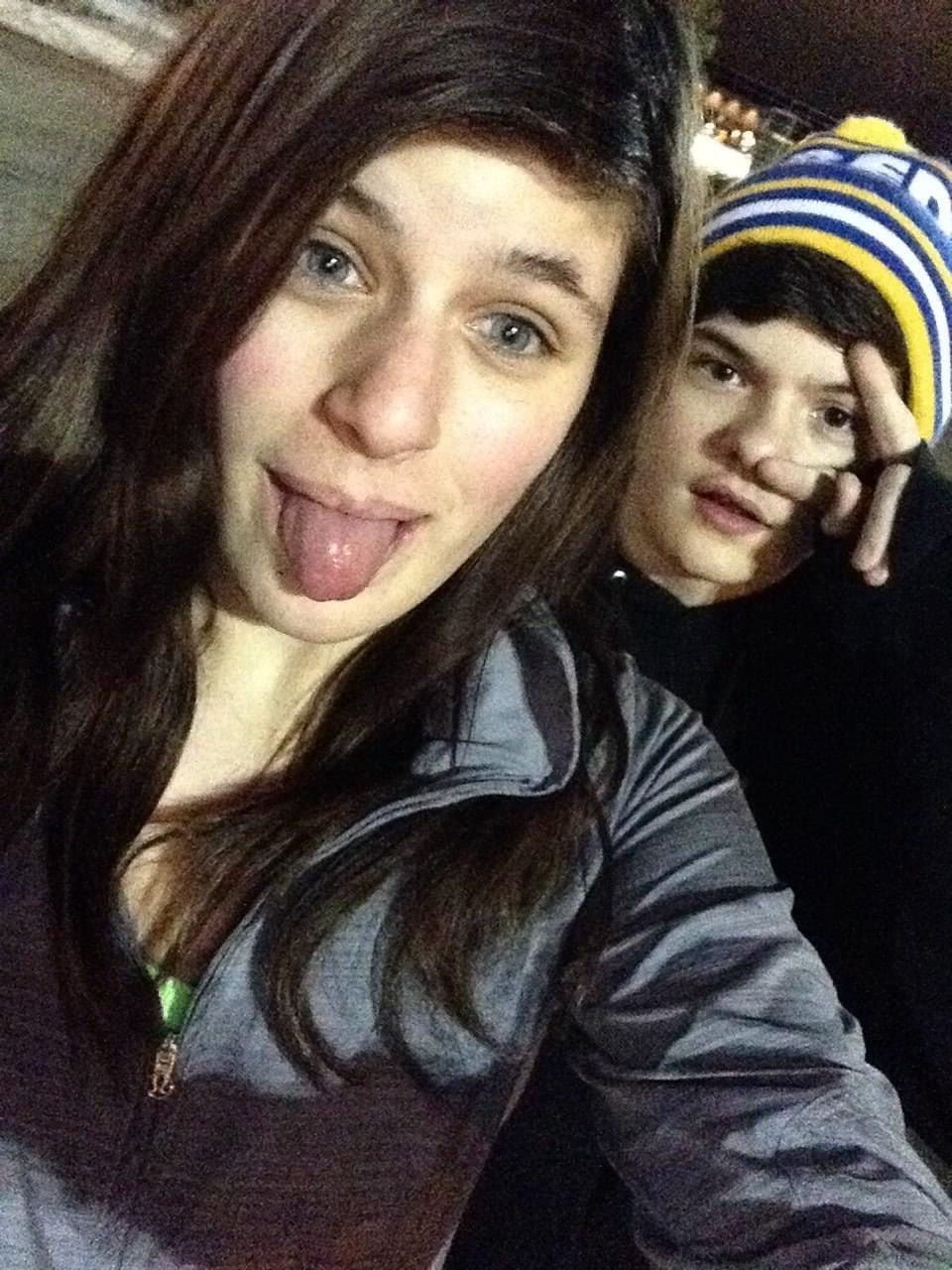 A girl sticking her tongue out next to a boy wearing a striped hat