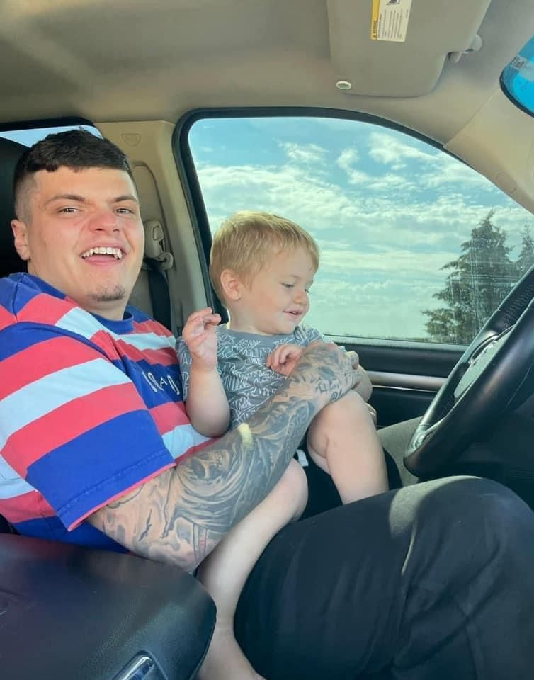 A man is holding a baby in his lap in a car.