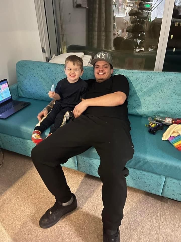 A man and a child are sitting on a blue couch.