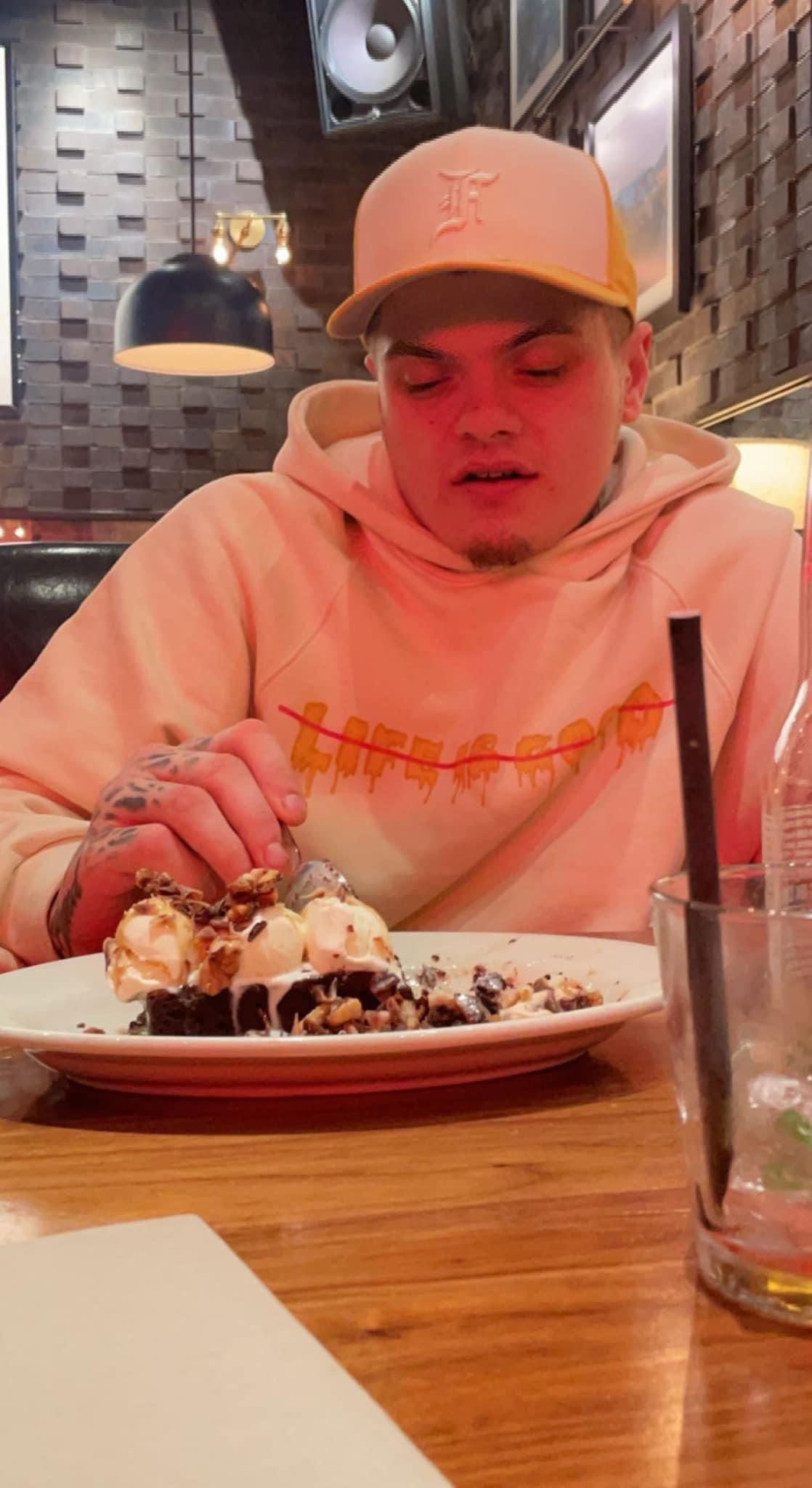 A man is sitting at a table eating a plate of food.