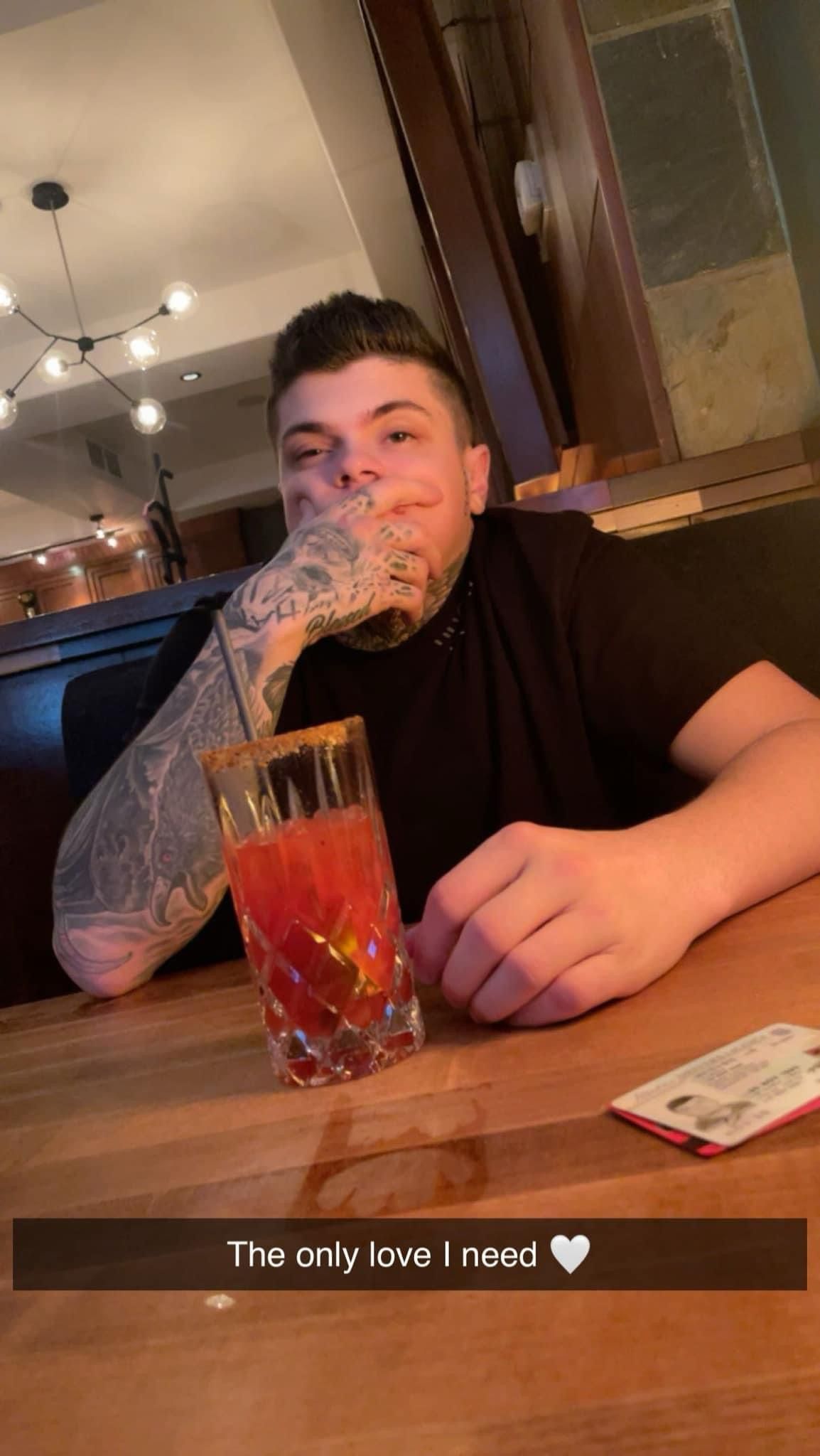 A man is sitting at a table with a drink in his hand.