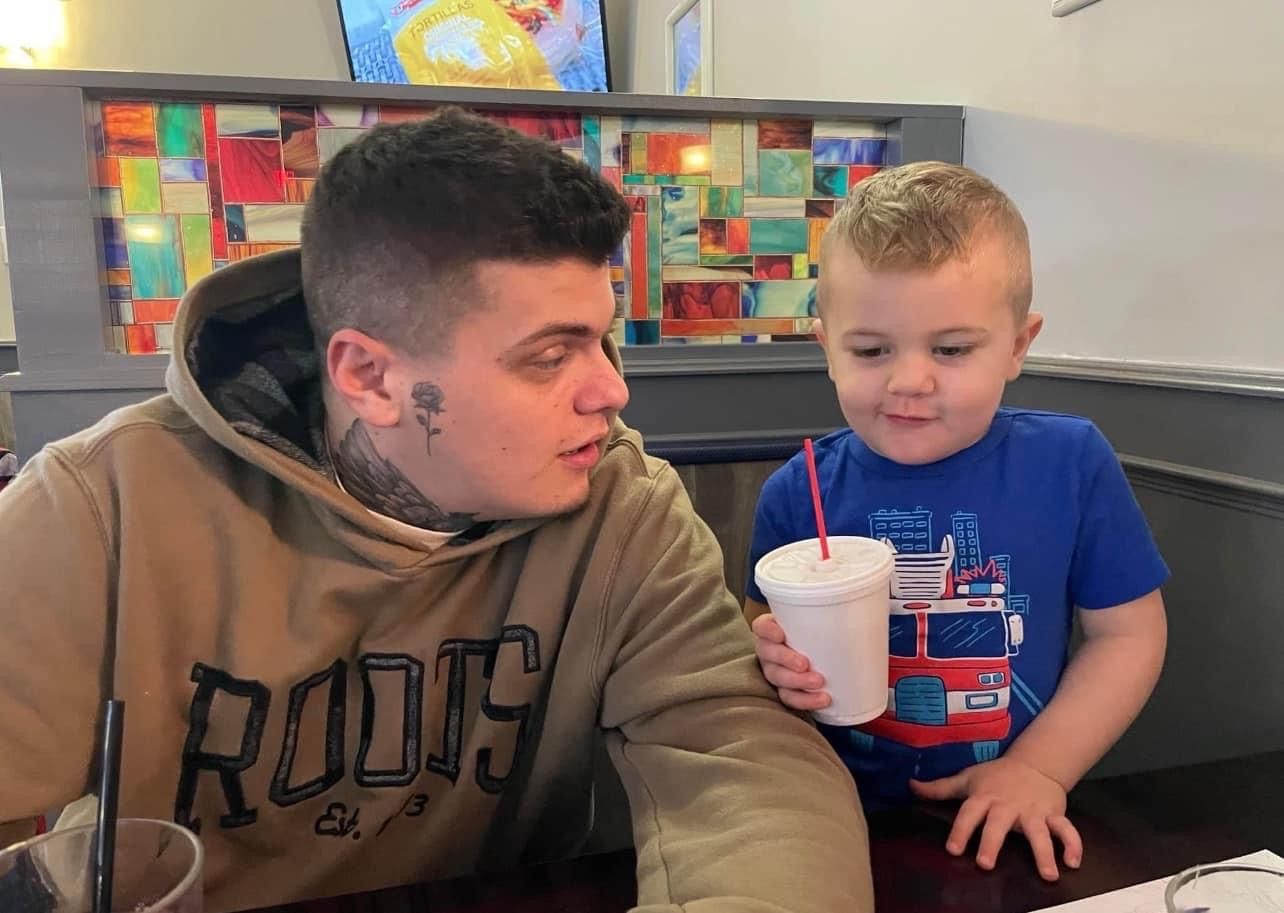 A man and a little boy are sitting at a table in a diner.