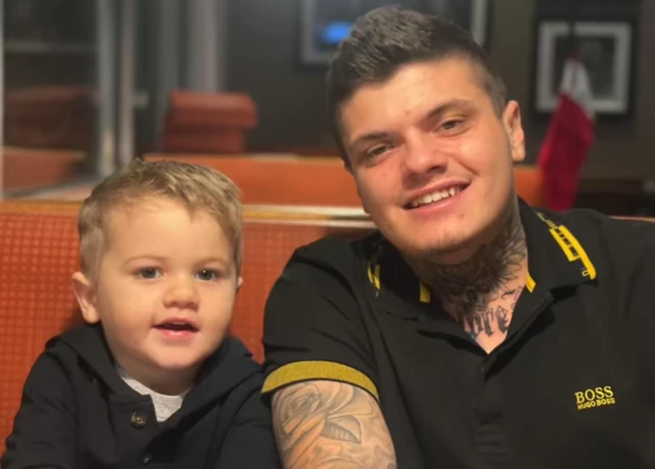 A man with a tattoo on his arm is sitting next to a little boy.