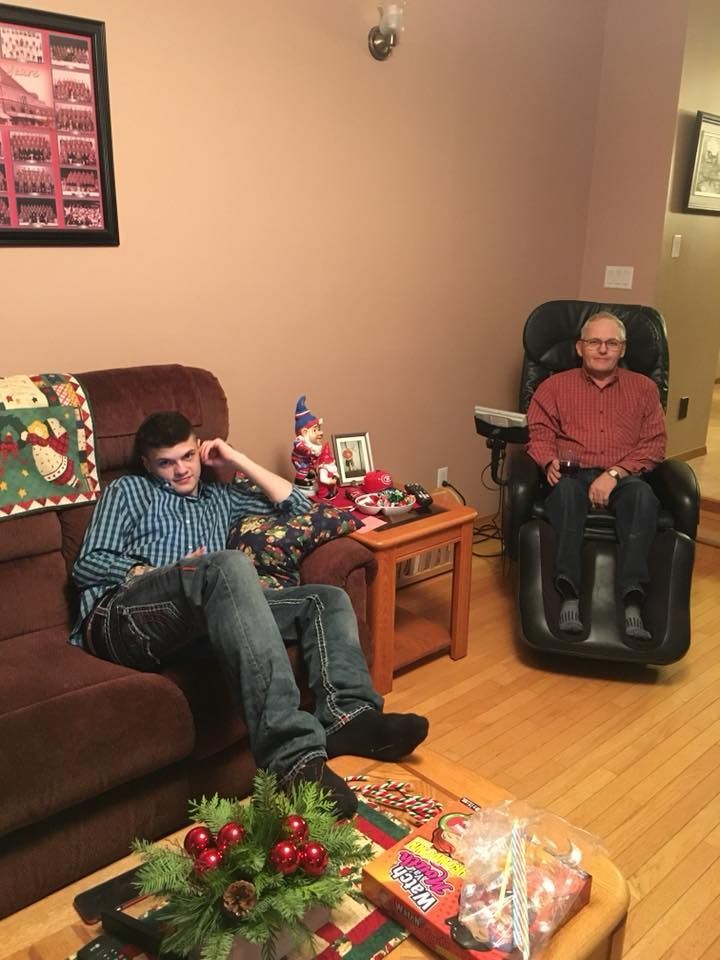 Two men are sitting on a couch in a living room.