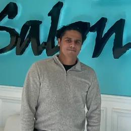 A man is standing in front of a sign that says salon