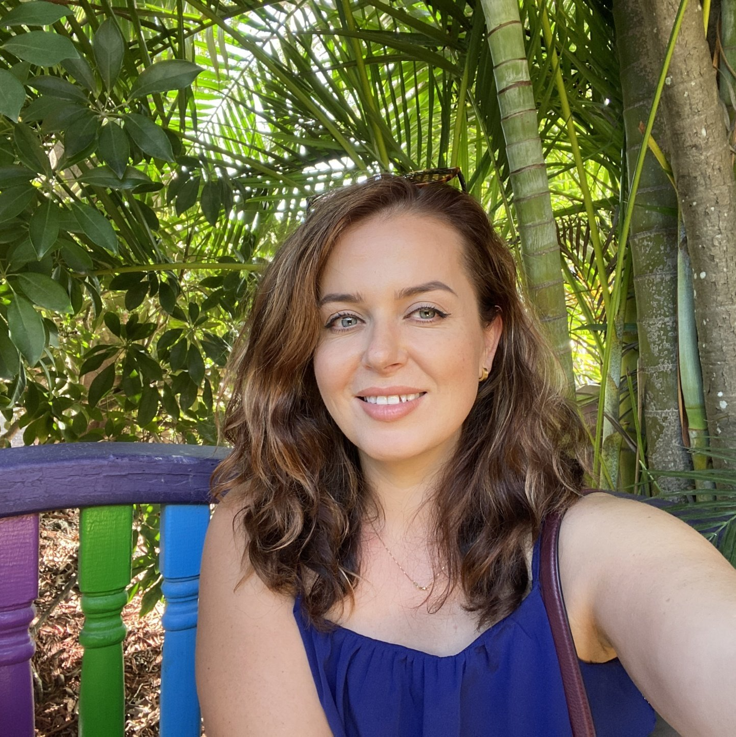 A woman is taking a selfie while sitting on a colorful bench.