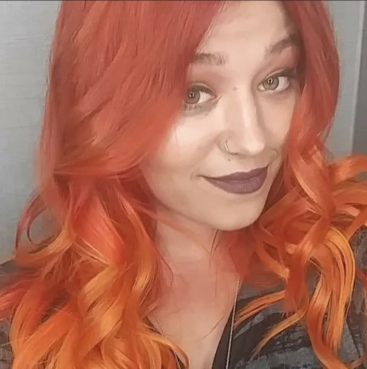 A woman with red hair and a nose ring is taking a selfie.