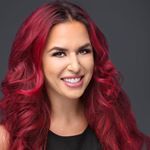 A woman with long red hair is smiling for the camera.