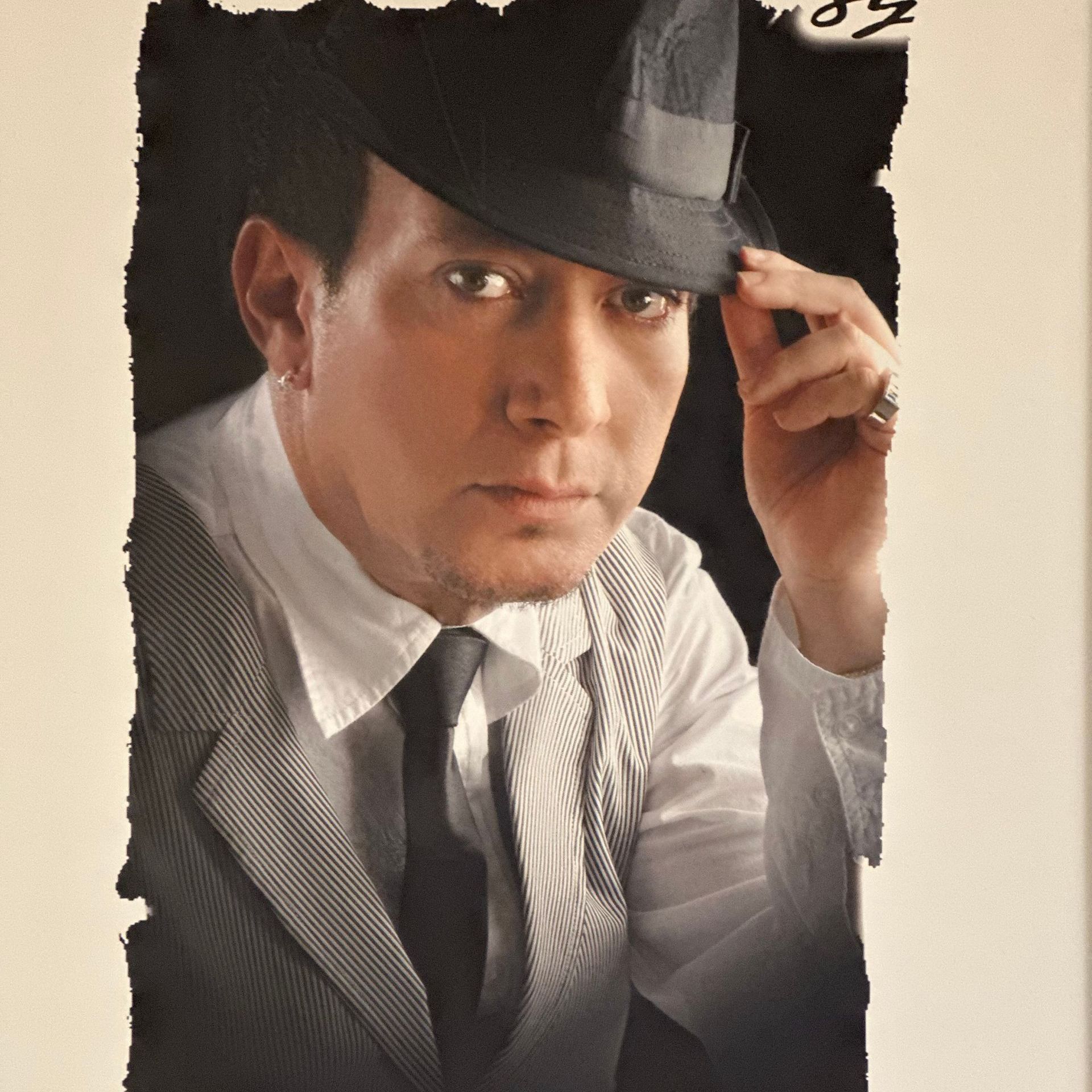 A man in a suit and tie adjusts his hat