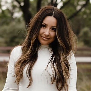 A woman with long brown hair is wearing a white turtleneck sweater.