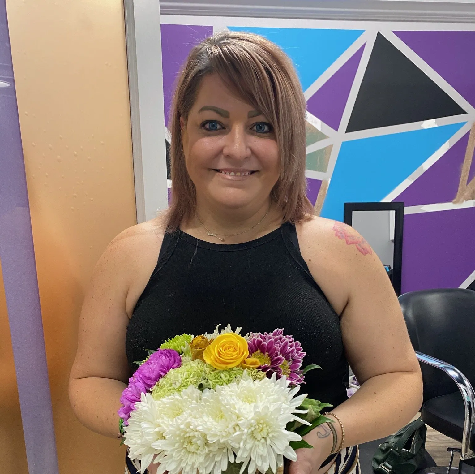 A woman in a black tank top is holding a bouquet of flowers.