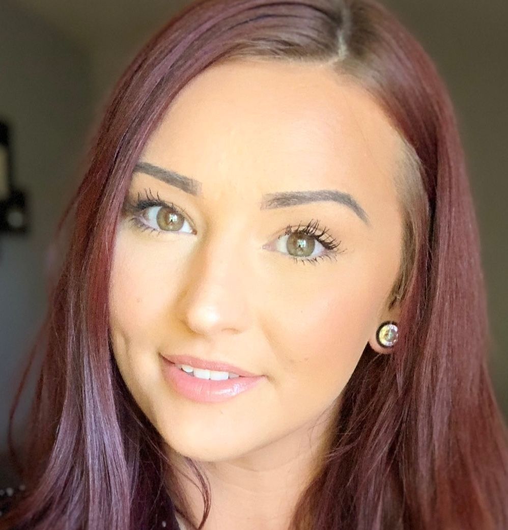 A close up of a woman 's face with long red hair and earrings.