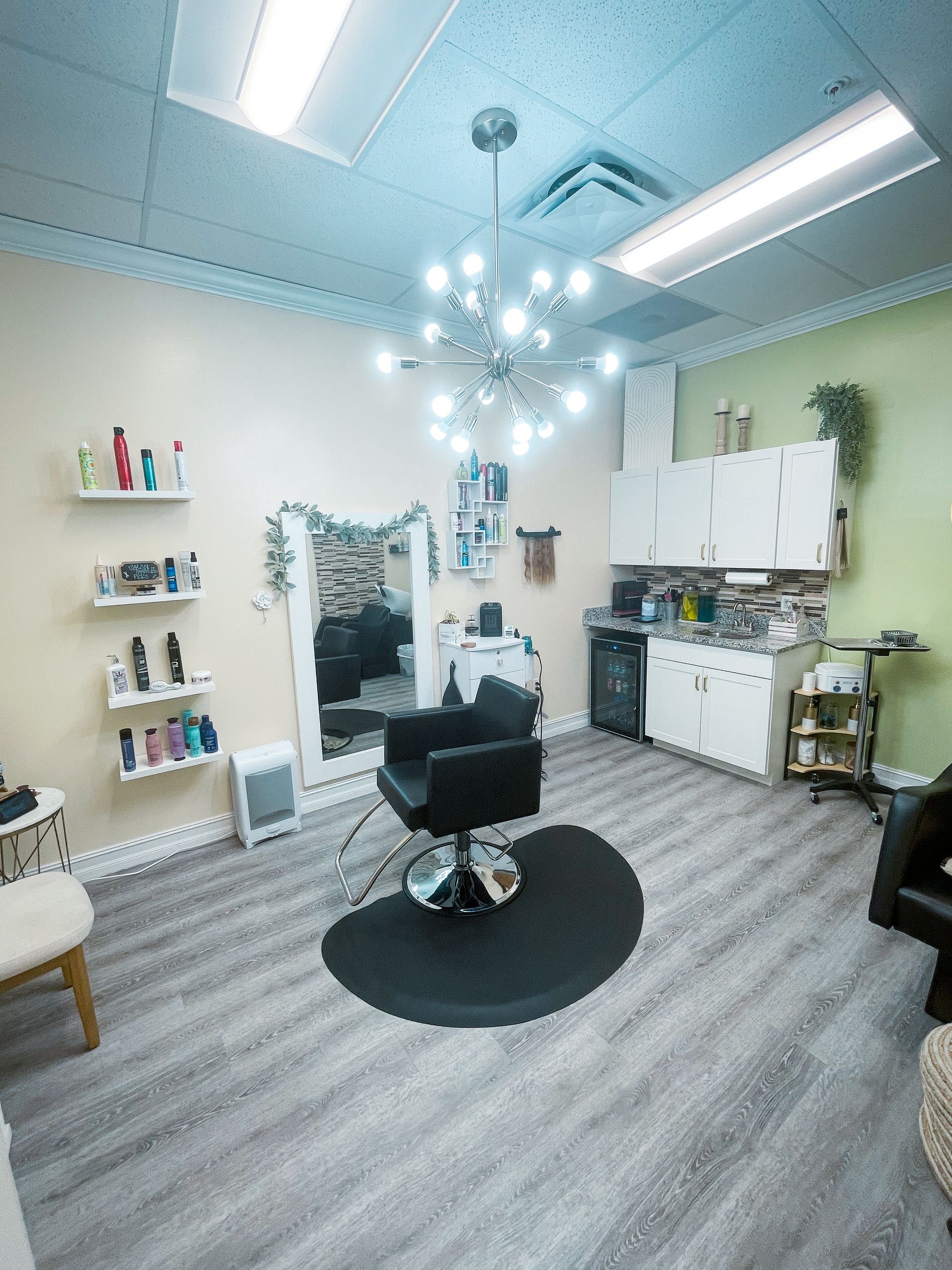 A hair salon with a chair , sink , and mirror.