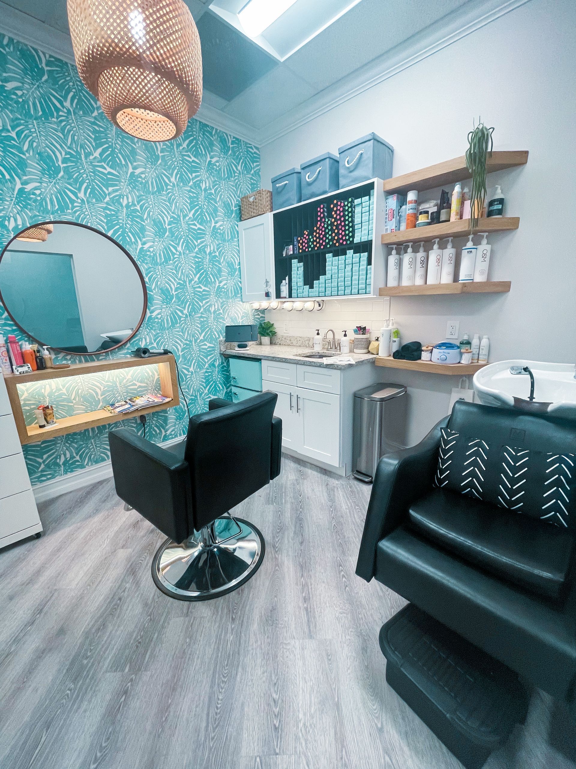A hair salon with a chair , sink , mirror and shelves.
