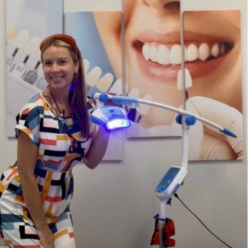 A woman in a colorful dress stands in front of a dental machine