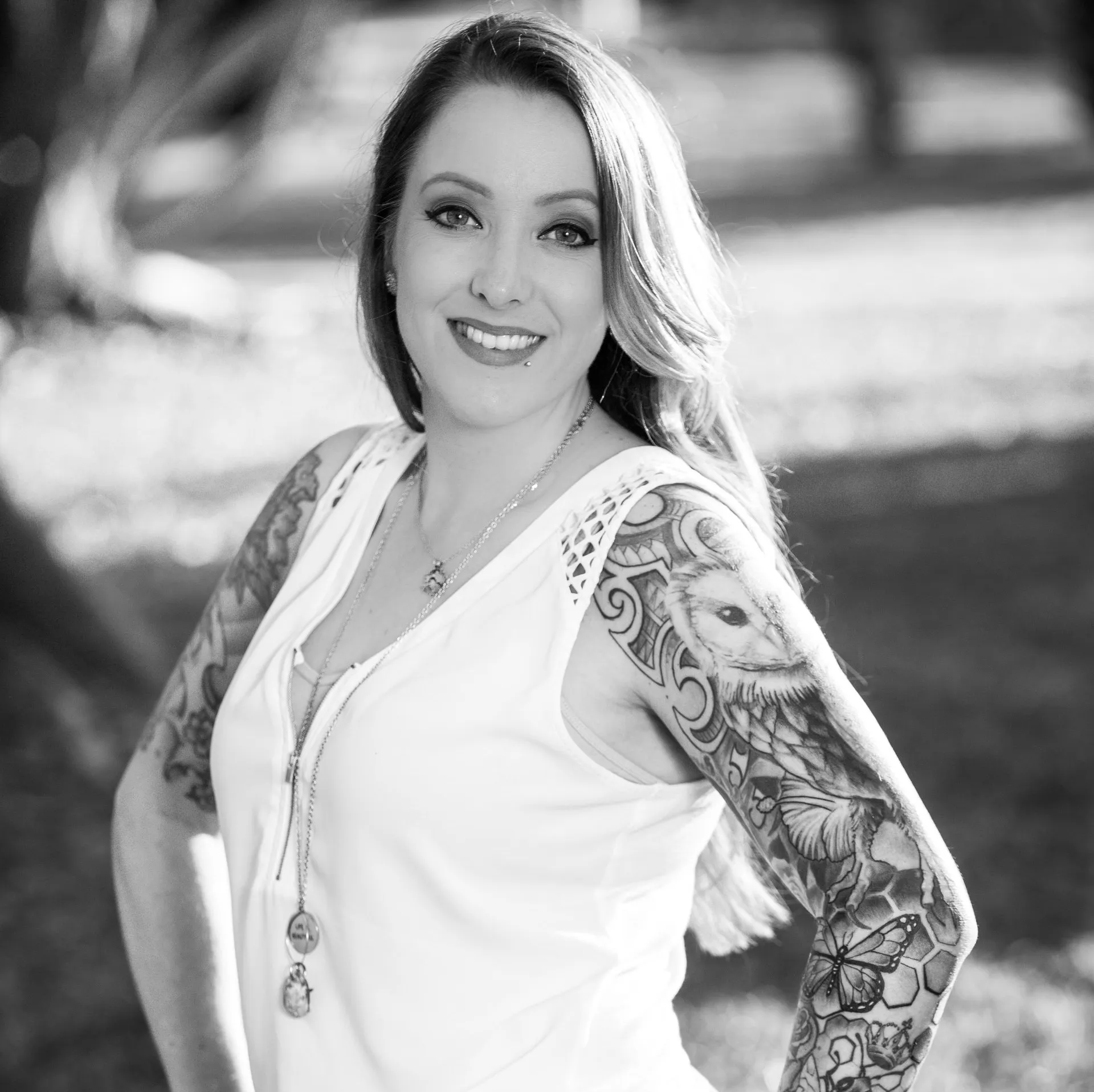 A black and white photo of a woman with tattoos on her arms.