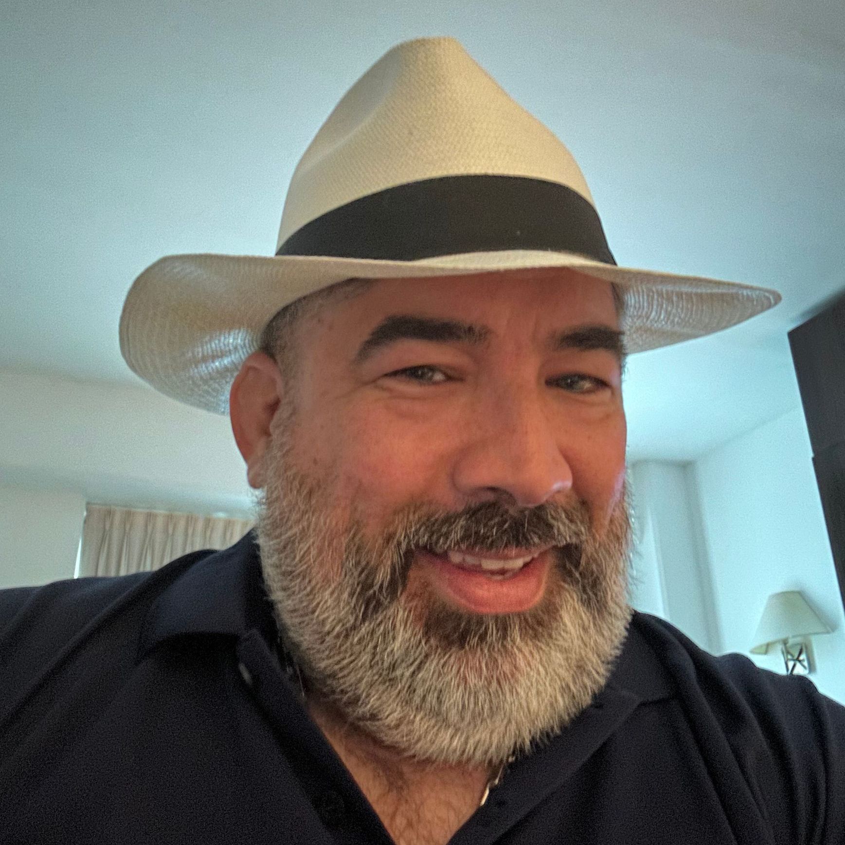 A man with a beard wearing a hat and smiling
