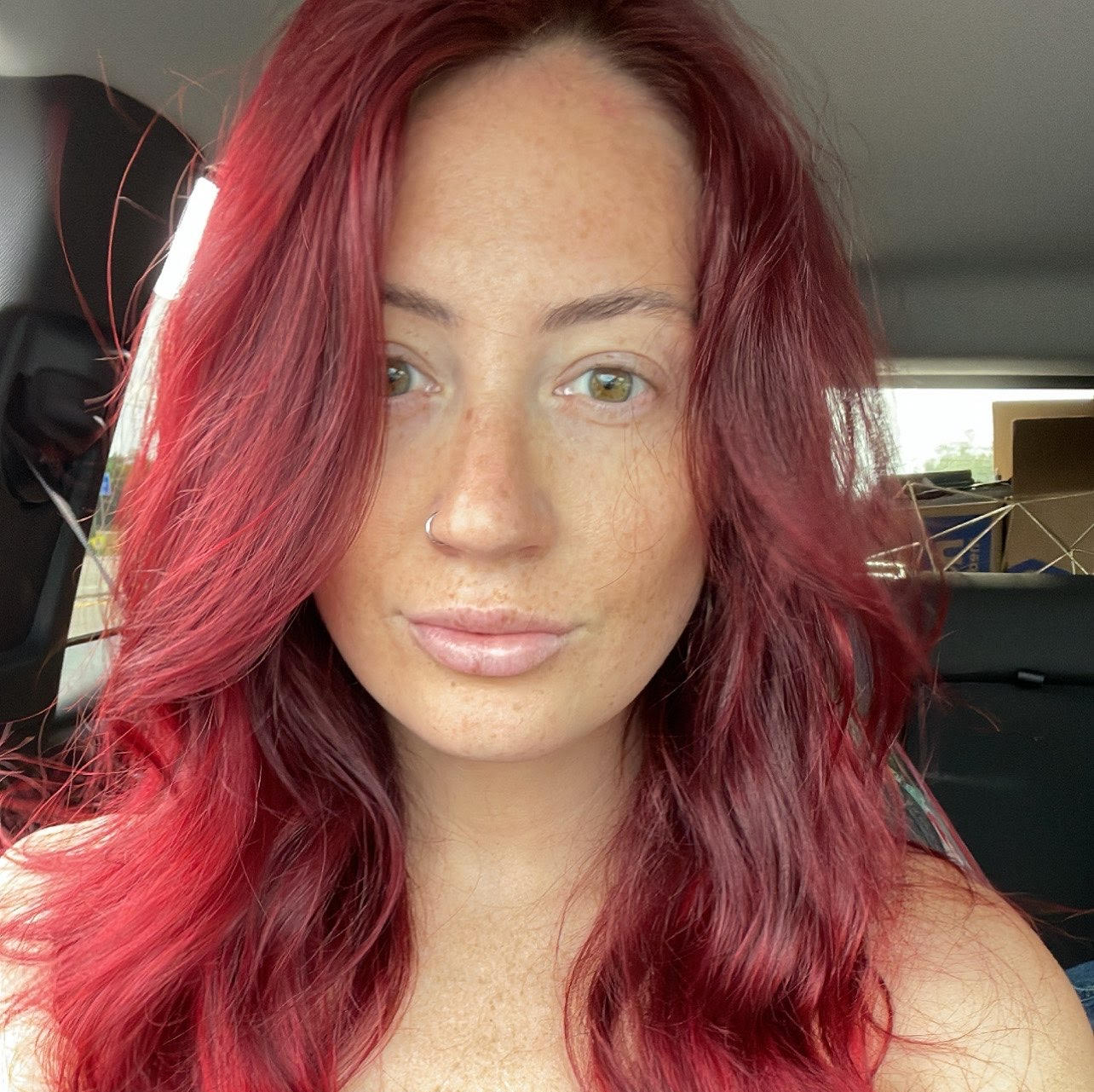 A woman with red hair is sitting in the back seat of a car.