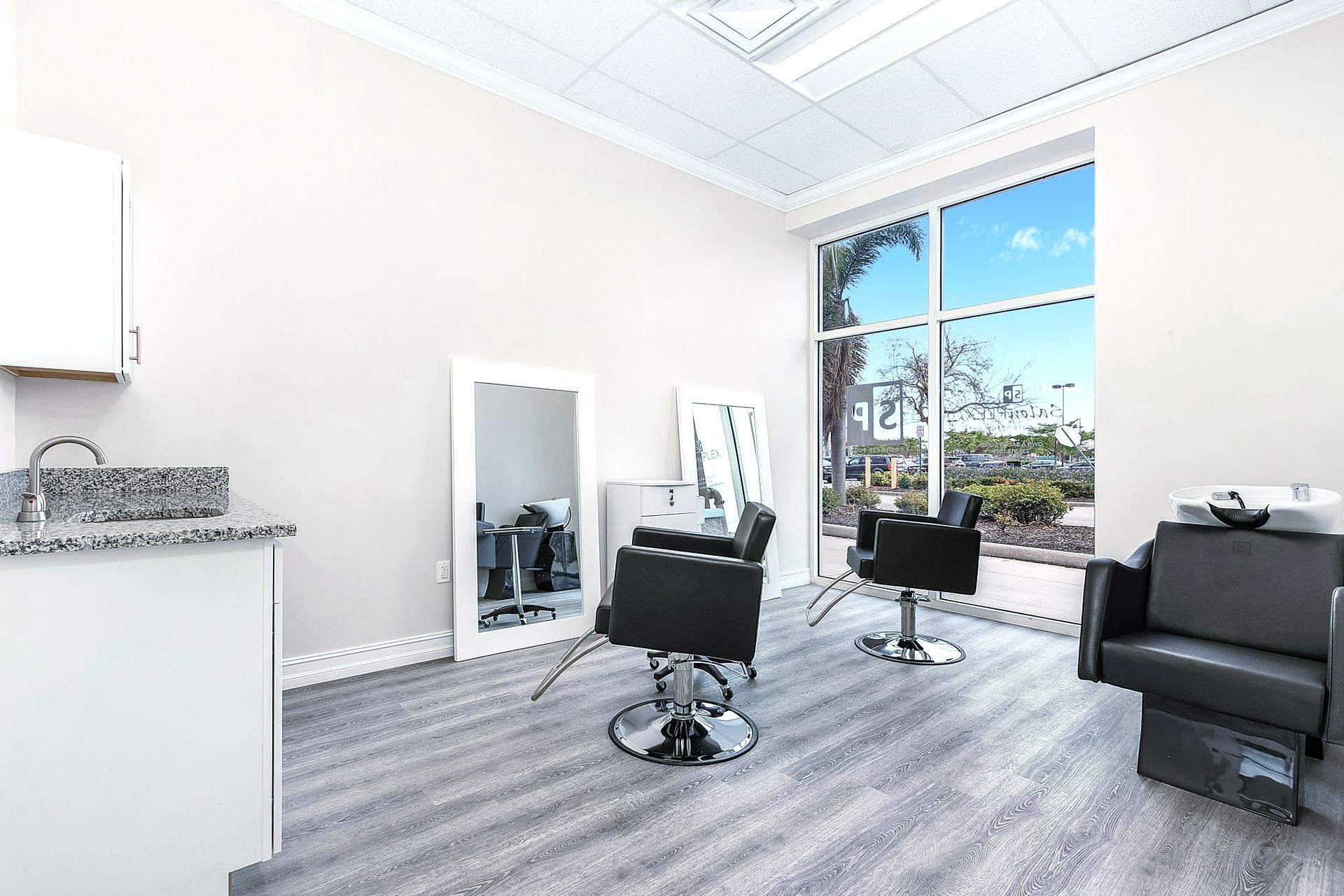 A salon with two chairs , a sink and a mirror.