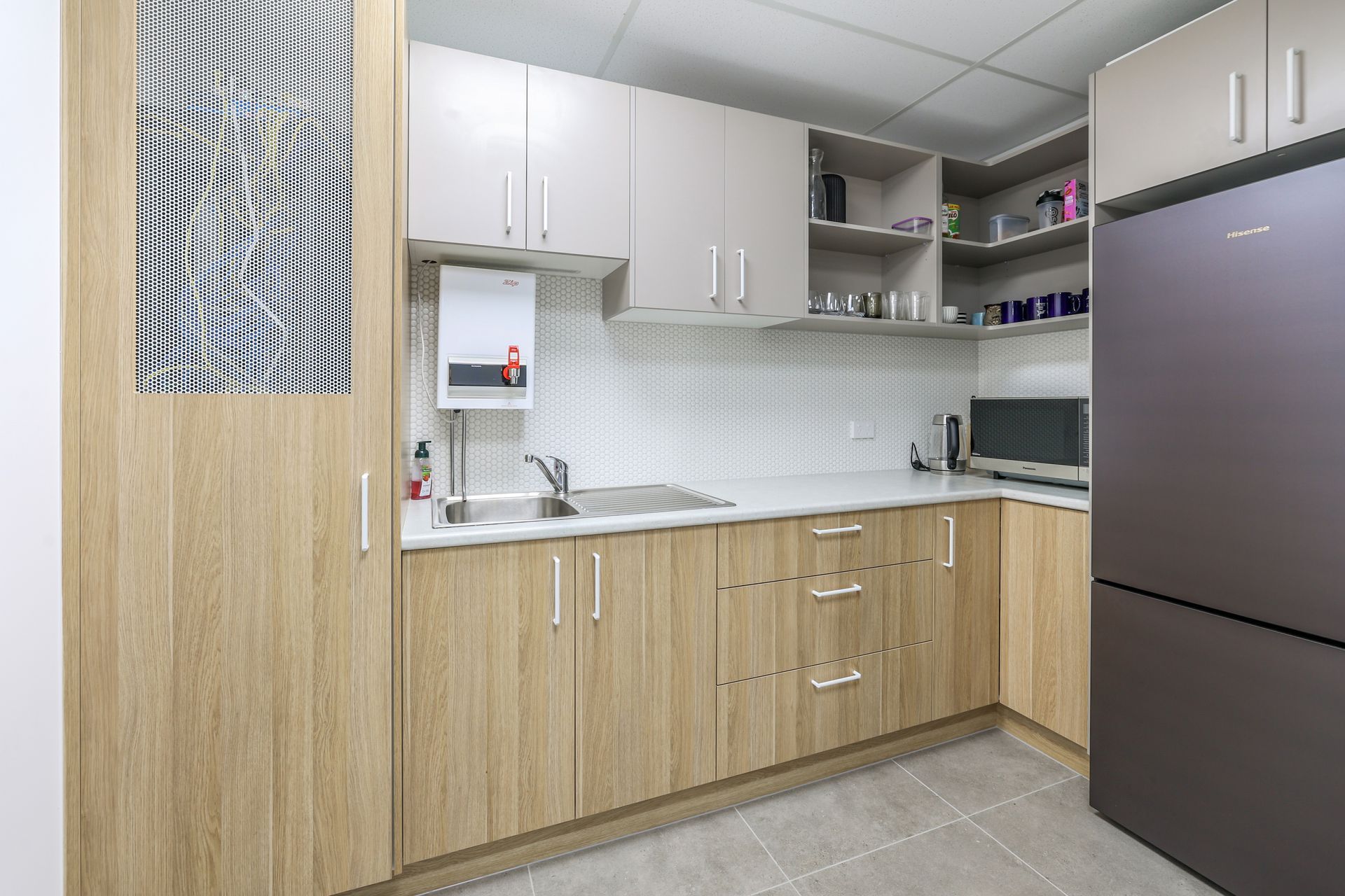 A kitchen with light wood cabinets, stainless steel appliances, and white countertops.