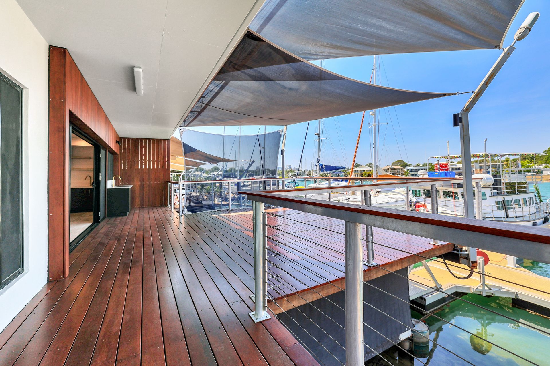 Wooden deck with a view of boats in the harbor, shaded by canvas canopies on a sunny day.