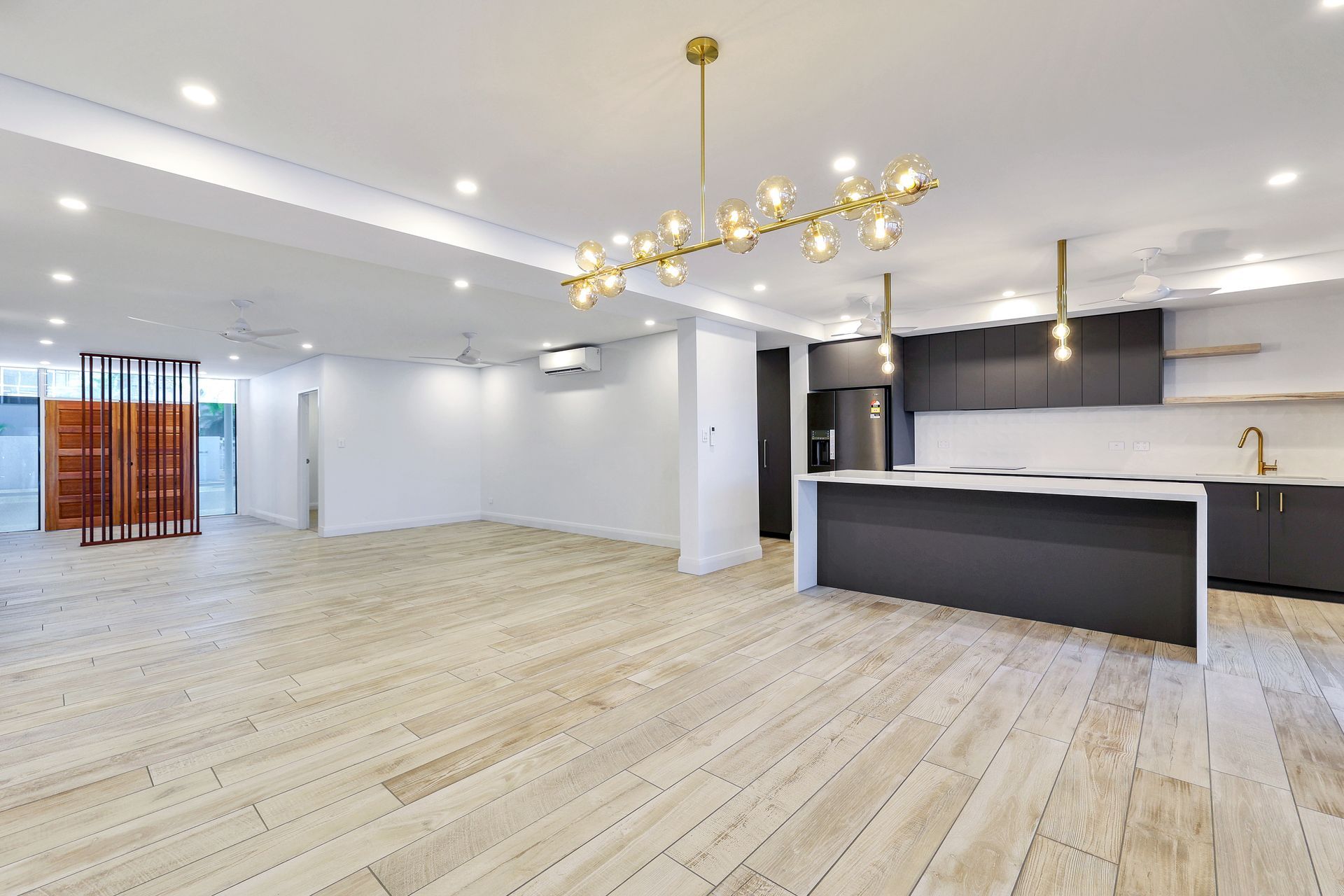 Modern open-concept kitchen and living area with dark gray cabinetry, island, and wood floors.